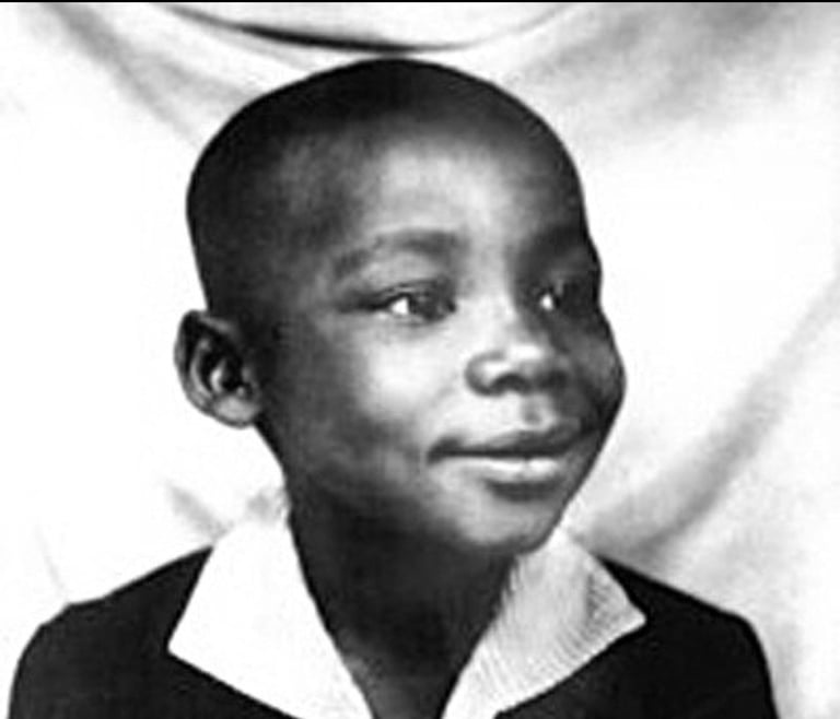 Black and white portrait photograph of a young man with short hair wearing a dark jacket over a white collared shirt